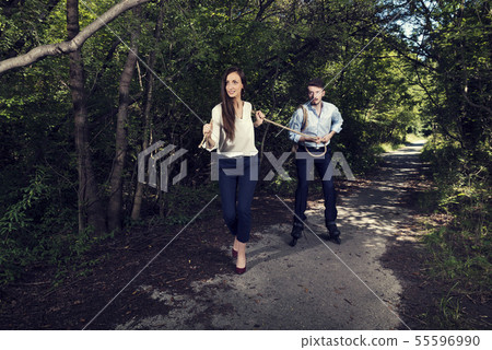 Business woman pulling one business man with rope Business woman pulling one business man with rope 55596990