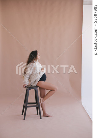 Pregnant woman with long hair in white sweater.  55597985