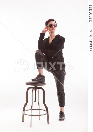 Young fashion model in trendy and casual clothes posing in studio using a chair over white 55601331