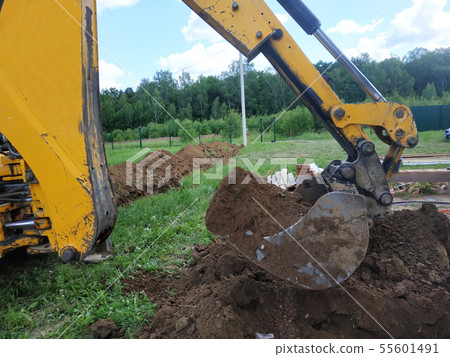 In a private plot, the excavator digs a trench. In a private plot, the excavator digs a trench. 55601491