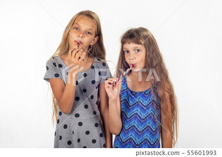 Two girls suck lollipops and look in the frame Two girls suck lollipops and look in the frame 55601993