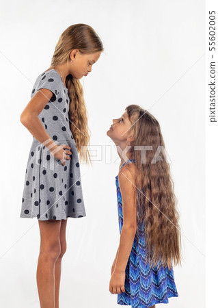 Two girls of different stature, one stood on a Two girls of different stature, one stood on a 55602005