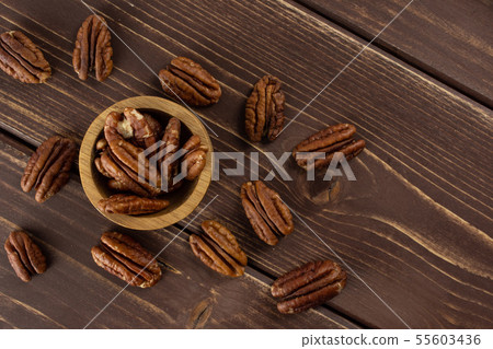 Fresh pecan nut on brown wood Fresh pecan nut on brown wood 55603436