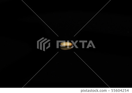 Unpeeled sesame seeds isolated on black glass Unpeeled sesame seeds isolated on black glass 55604254