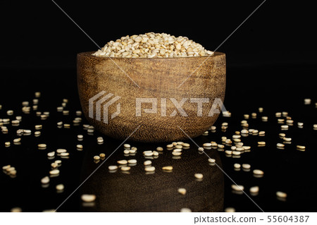 Unpeeled sesame seeds isolated on black glass Unpeeled sesame seeds isolated on black glass 55604387