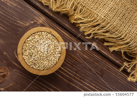 Unpeeled sesame seeds on brown wood 55604577