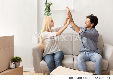 New Home. Happy Couple Giving High Five Sitting On Couch New Home. Happy Couple Giving High Five Sitting On Couch 55604974