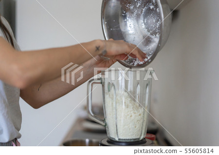 Woman pouring cottage cheese into a blender in the kitchen Woman pouring cottage cheese into a blender in the kitchen 55605814