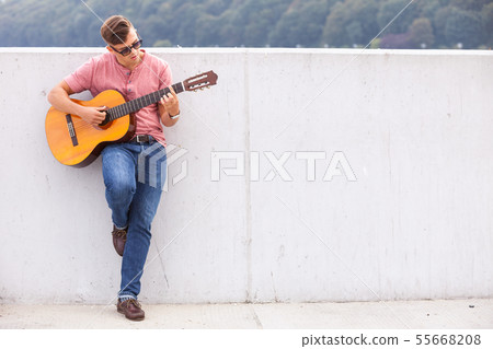 Man with guitar leaning on wall. Man with guitar leaning on wall. 55668208
