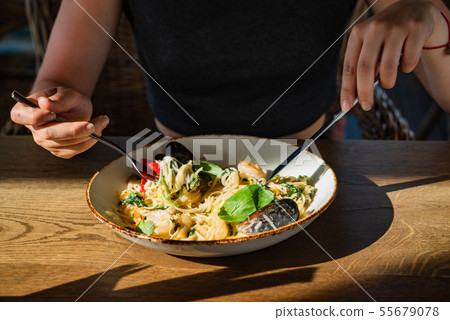 woman eating seafood pasta in the cafe woman eating seafood pasta in the cafe 55679078
