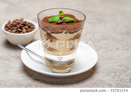 Classic tiramisu dessert in a glass cup on plate and coffee beans on concrete background 55701554