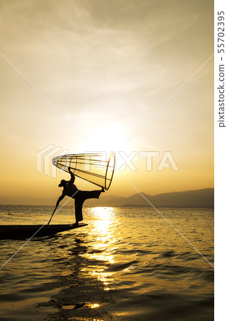 Silhouette Burmese fisherman on wood boat catching 55702395