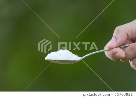 Hand is holding a spoon with monosodium glutamate 55703921