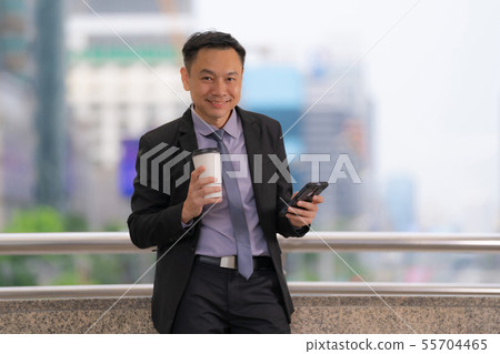 Asian Businessman standing and holding mobile 55704465