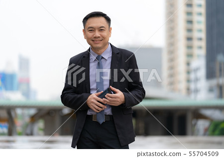 Asian Businessman standing and holding mobile 55704509