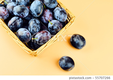 Plums in basket isolated on beige background 55707266