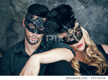 Beautiful couple in mysterious black mask sitting on floor in studio Beautiful couple in mysterious black mask sitting on floor in studio 55710226