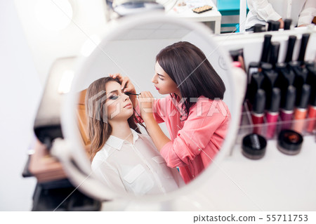 beauty and makeup concept - closeup portrait of beautiful woman getting professional make-up with 55711753