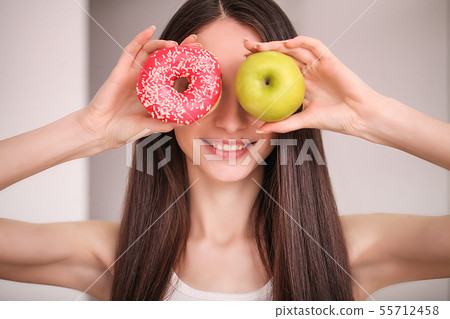 Diet. Woman Measuring Body Weight On Weighing Scale Holding Donut and apple. Sweets Are Unhealthy 55712458