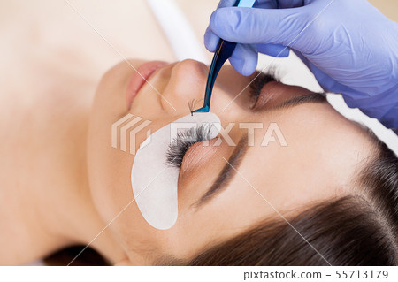 Woman Eye with Long Eyelashes. Beautiful Young Woman During Eyelash Extension Woman Eye with Long Eyelashes. Beautiful Young Woman During Eyelash Extension 55713179
