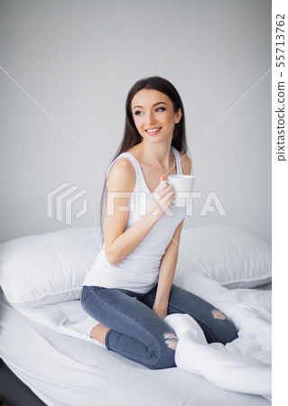 Relaxing On Bed During Weekend. Beautiful Woman Relaxing on a Bed and Looking Happy 55713762