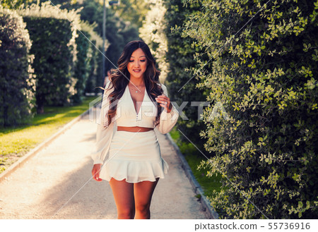 Beautiful Asian girl in white dress smiling in the park Beautiful Asian girl in white dress smiling in the park 55736916