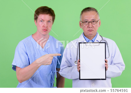 Mature Japanese man doctor with Scandinavian man patient showing clipboard together Mature Japanese man doctor with Scandinavian man patient showing clipboard together 55764591