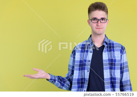 Young handsome hipster man with eyeglasses showing something Young handsome hipster man with eyeglasses showing something 55766519