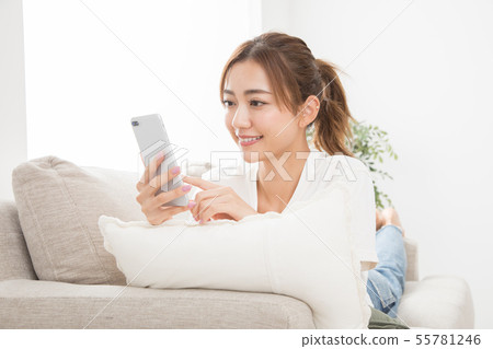 使用智能手機的婦女在沙發 使用智能手機的婦女在沙發 55781246