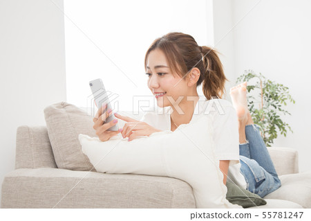 使用智能手機的婦女在沙發 使用智能手機的婦女在沙發 55781247