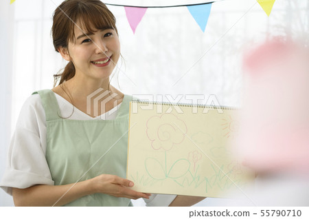 A nursery teacher (teacher) sitting on the floor and talking to the child 55790710