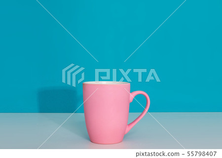 Pink cup on light surface on bright blue background 55798407