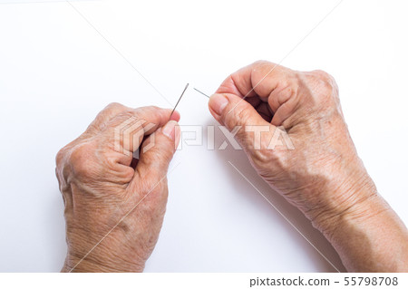Senior woman's hands trying to thread a needle 55798708