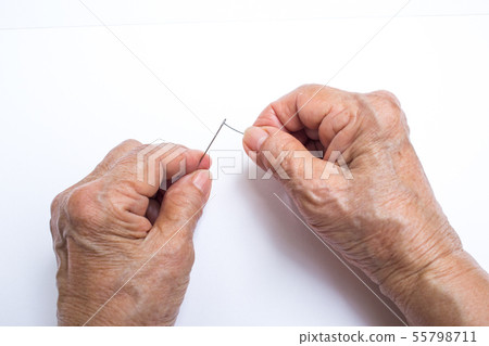 Senior woman's hands trying to thread a needle 55798711