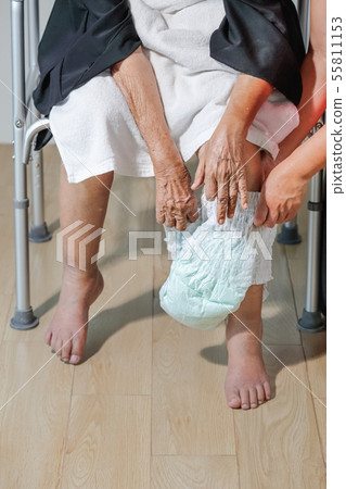 elderly woman changing diaper with caregiver 55811153
