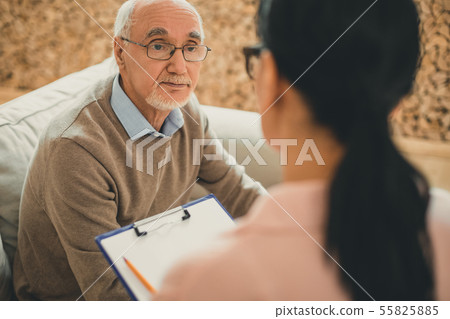 Senior with grey hair directly looking on dark-haired woman 55825885