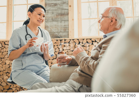 Smiling kind woman sitting in chair against old man 55827360