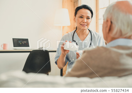 Old grey-haired man and his nurse sitting in consulting room 55827434