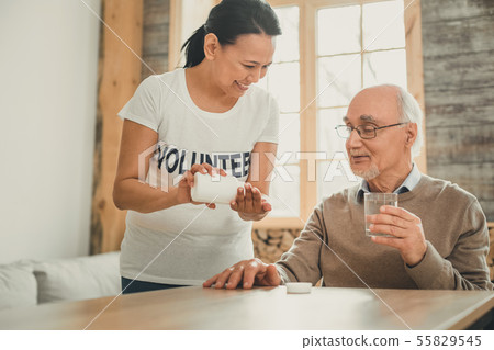 Joyful long-haired lady shaking out pills from white container 55829545