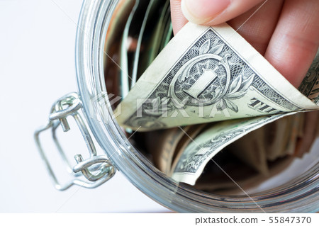Hand pulls one dollar banknote in glass jar Hand pulls one dollar banknote in glass jar 55847370
