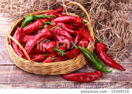 Wicker basket full of fresh red chili peppers. 55849518