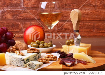 Assortment of cheese with fruits, grapes, nuts and cheese knife on a wooden serving tray. 55850415