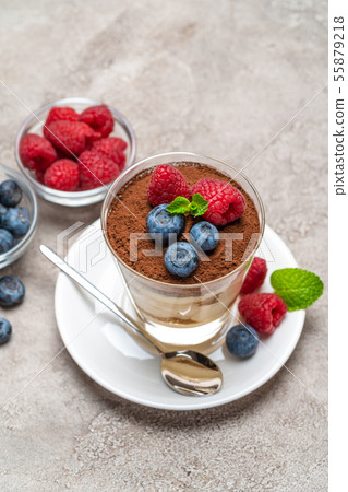 Classic tiramisu dessert with blueberries and raspberries in a glass and bowls with berries on Classic tiramisu dessert with blueberries and raspberries in a glass and bowls with berries on 55879218