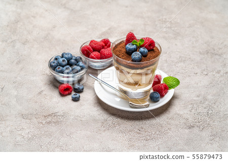 Classic tiramisu dessert with blueberries and raspberries in a glass and bowls with berries on Classic tiramisu dessert with blueberries and raspberries in a glass and bowls with berries on 55879473