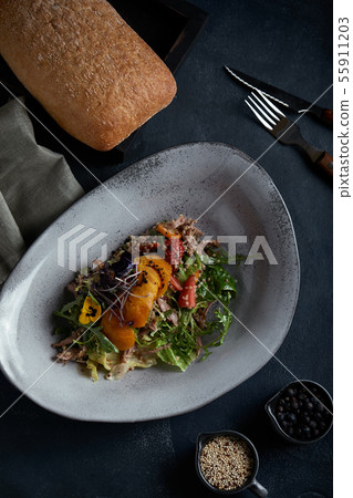 Salad with duck strawberries and mango on a dark background, low key. Food photo concept. Restaurant 55911203