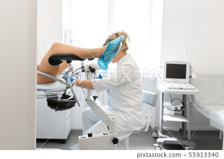 A gynecologist examines a patient on a 55913340