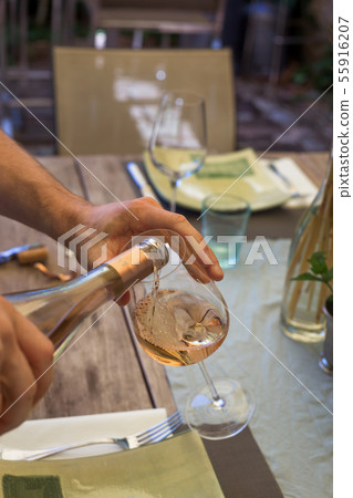 Man is blue tee-shirt is opening wine bottle rustic background. Celebration concept. Man is blue tee-shirt is opening wine bottle rustic background. Celebration concept. 55916207