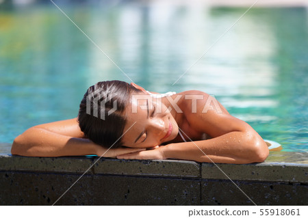 Asian woman relaxing sunbathing - pool spa retreat Asian woman relaxing sunbathing - pool spa retreat 55918061