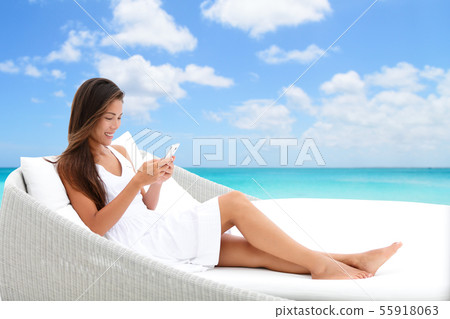 Smartphone woman using phone app on beach bed sofa Smartphone woman using phone app on beach bed sofa 55918063