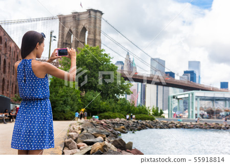 Tourist taking travel picture with phone of Brooklyn bridge, New York Tourist taking travel picture with phone of Brooklyn bridge, New York 55918814